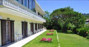 a building with a yard with tables and chairs and flowers at Family Studios in Marathias