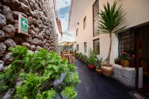 a courtyard with potted plants and tables and a building at Hotel Boutique Gold Garden in Cusco