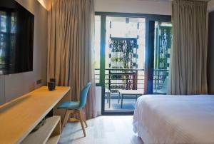 a bedroom with a bed and a desk and a balcony at La Capilla - Punta del Este in Punta del Este