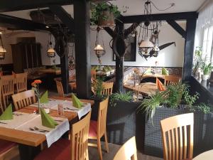 un restaurante con mesas de madera, sillas y plantas en Andi´s Steakhüsli & Hotel, en Schopfheim