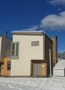 a white building with a door in the snow at Chalet adosado entero, bbq y piscina comunitaria in Sabiñánigo