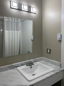 Imperial Motel في One Hundred Mile House: حمام مع حوض ومرآة كبيرة