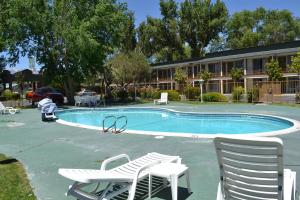 a swimming pool with two chairs and a building at Vagabond Inn Bishop in Bishop