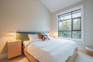 a bedroom with a white bed and a window at Fitzsimmons Walk by Outpost Whistler in Whistler