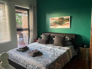 a green bedroom with a bed with two towels on it at Weaver Place in Bloubergstrand