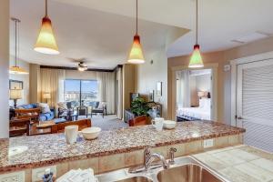 a kitchen with a sink and a living room at Origin at Seahaven #831 by Book That Condo in Panama City Beach