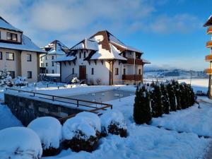 une maison recouverte de neige avec des buissons enneigés dans l'établissement Zlatibor Hills Zeus, à Zlatibor