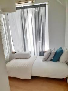 Bett mit weißer Bettwäsche und Kissen vor einem Fenster in der Unterkunft Olival Home- Feels like home in Lissabon