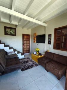 ein Wohnzimmer mit 2 Sofas und einem TV in der Unterkunft refugio vo olino in Imbituba