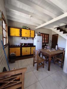 eine Küche mit einem Holztisch und gelben Schränken in der Unterkunft refugio vo olino in Imbituba