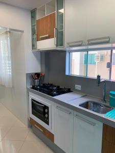 a kitchen with white cabinets and a stove and a sink at Amplo e Confortável in Itapema