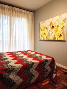 a bedroom with a bed and a painting on the wall at Studioaconchegantepoa in Porto Alegre