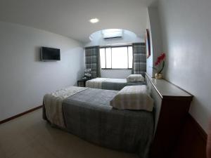 a bedroom with two beds and a window at Apartamento em frente ao mar Praia da Costa in Vila Velha