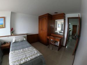 a bedroom with a bed and a desk and a mirror at Apartamento em frente ao mar Praia da Costa in Vila Velha