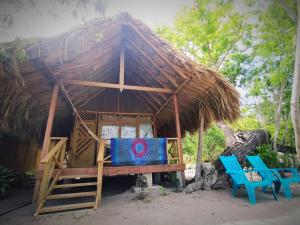 uma pequena cabana com duas cadeiras azuis e um telhado de palha em Centro Ubuntu em Isla Grande