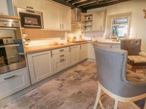 a kitchen with white cabinets and a blue chair in it at Bryn Y Bwyd Farm House in Barmouth
