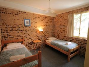 een slaapkamer met 2 bedden en een bakstenen muur bij Twin Seasons 4 Lake and Mountain Views in Jindabyne