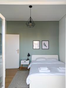 a white bedroom with a white bed and a chandelier at Hygge Home at Trikala in Tríkala