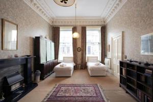 uma sala de estar com duas cadeiras e uma televisão e um sofá em Quirky, West End, Edinburgh House em Edinburgo