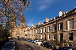 a street with cars parked in front of a building at Quirky, West End, Edinburgh House in Edinburgh