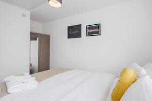 a bedroom with a white bed with a yellow pillow at Dartford Kent Smart Nest in Dartford
