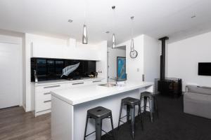 a kitchen with a white counter and stools at Silver Fern - Lake Tekapo in Lake Tekapo