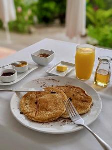 a plate of pancakes and a glass of orange juice at Terramaya Boutique Hotel in Copan Ruinas