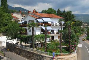 a building with palm trees in front of a street at Guesthouse Villa Stanger in Lovran