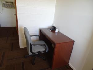 d'un bureau avec une chaise et un téléphone. dans l'établissement PRAIRIE WINDs MOTEL CARTHAGE, 