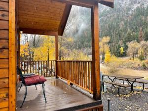 a porch of a cabin with a table and a bench at Ouray Riverside Resort - Inn & Cabins in Ouray