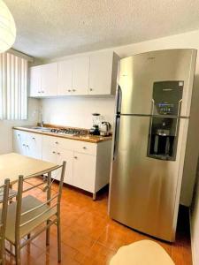 a kitchen with a stainless steel refrigerator and a table at DEPTO FRENTE AL AUTODROMO HMNOS A 10 MIN CAMINANDO in Mexico City