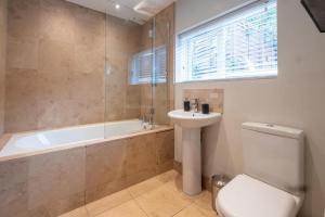 a bathroom with a toilet and a tub and a sink at Sailmaker's Cottage in Lymington