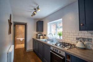 uma cozinha com um lavatório e um fogão forno superior em Sailmaker's Cottage em Lymington