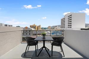a table and chairs on a balcony with a view at Gilligan's Hotel & Resort Cairns in Cairns