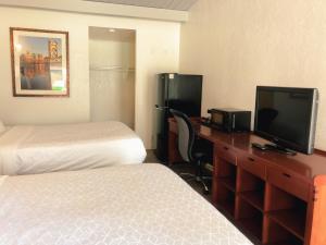 サンノゼにあるExtended Studio Suitesのベッド2台、デスク、テレビが備わるホテルルームです。