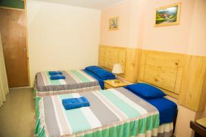 zwei Betten in einem Zimmer mit blauen Kissen in der Unterkunft Estancia Saraja in Ica