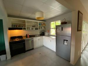 Una cocina con gabinetes blancos y un refrigerador. en Beautiful Villa, en Las Uvas