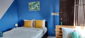 a bedroom with blue walls and a bed with yellow pillows at Hua Hin Paradise Guesthouse in Hua Hin