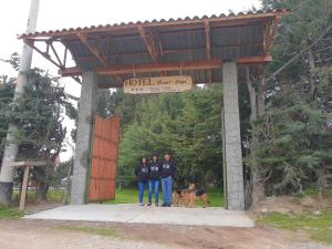 drie personen en een hond staan onder het bord van de parkeerplaats van het hotel bij RESORT ALAPA in Huancayo