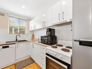 a kitchen with white cabinets and a stove top oven at Thurlow Avenue 49 Unit 1 in Nelson Bay