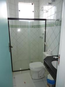a bathroom with a toilet and a glass shower at Pousada Cardoso in Ipiaú
