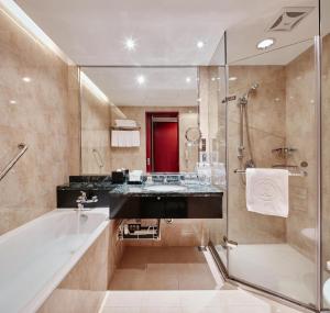 a bathroom with a tub, sink, and mirror at The Howard Plaza Hotel Taipei in Taipei
