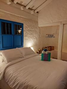 a bedroom with a large white bed with a blue window at El Oteo Tiny house. in Villa de Leyva