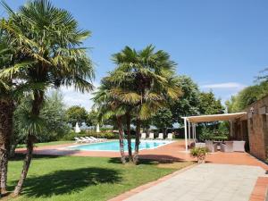 a swimming pool with palm trees next to a house at Timeless Tuscan Holiday Stay in Arezzo
