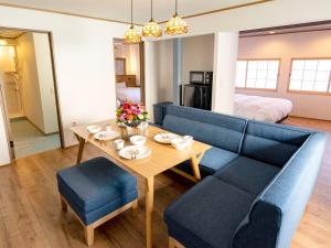 un soggiorno con tavolo e divano blu di Ebisumachi Takadaya a Hakodate