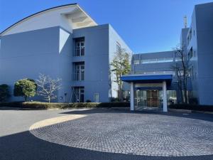 a white building with a circular driveway in front of it at 湘南リリーフ in Yokosuka
