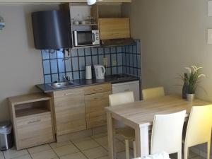 une cuisine avec une table en bois, une table et des chaises dans l'établissement Condo Gardens Leuven - Budget Studio Twin, à Louvain