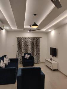 a living room with two chairs and a flat screen tv at Chillx comfort stay 2bhk luxury apt in Arpora