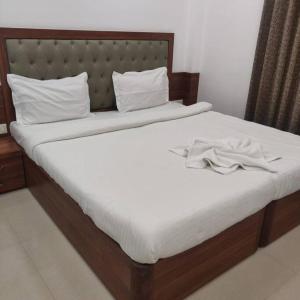 1 cama con sábanas blancas y cabecero de madera en Chillx comfort stay 2bhk luxury apt en Arpora