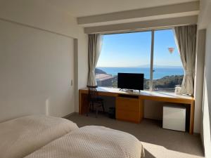 1 dormitorio con escritorio, ordenador y ventana en 湘南リリーフ, en Yokosuka